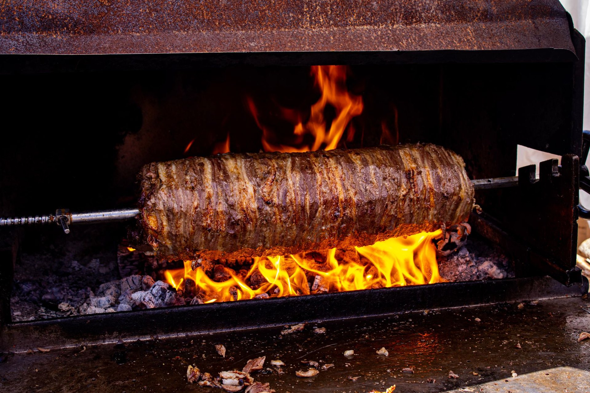 Felülnézet napsütötte piknikről a füvön: elviteles dobozokból esznek steakburgonyát, a dobozok takarókon állnak.