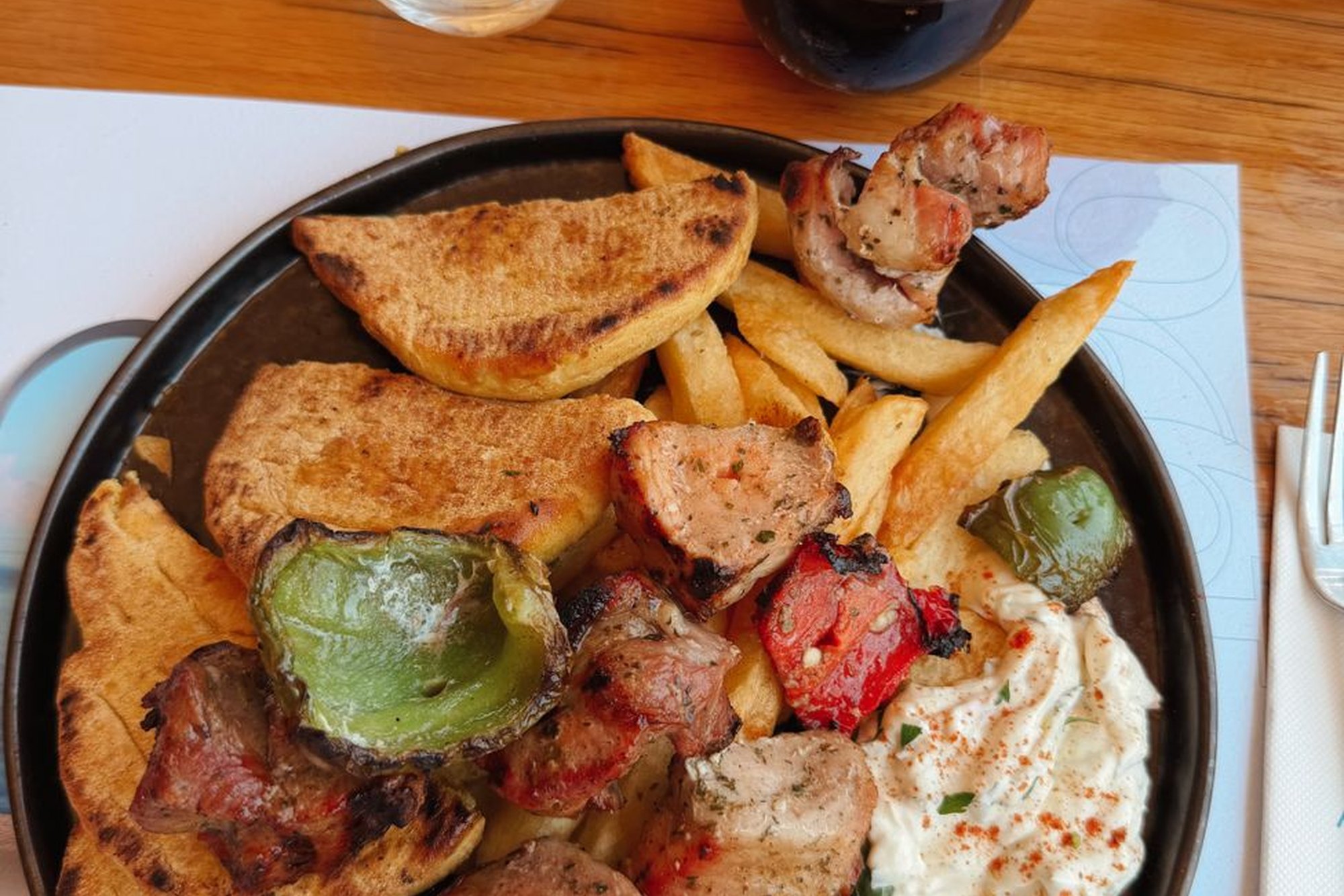 Három mosolygó barát ül az asztal körül, nevetve esznek együtt gyros pitát.