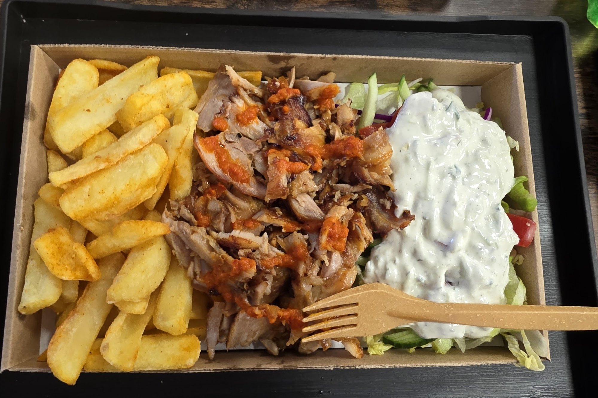 Közeli: valaki egy gyros pitát tart a kezében, piros szalvétán.