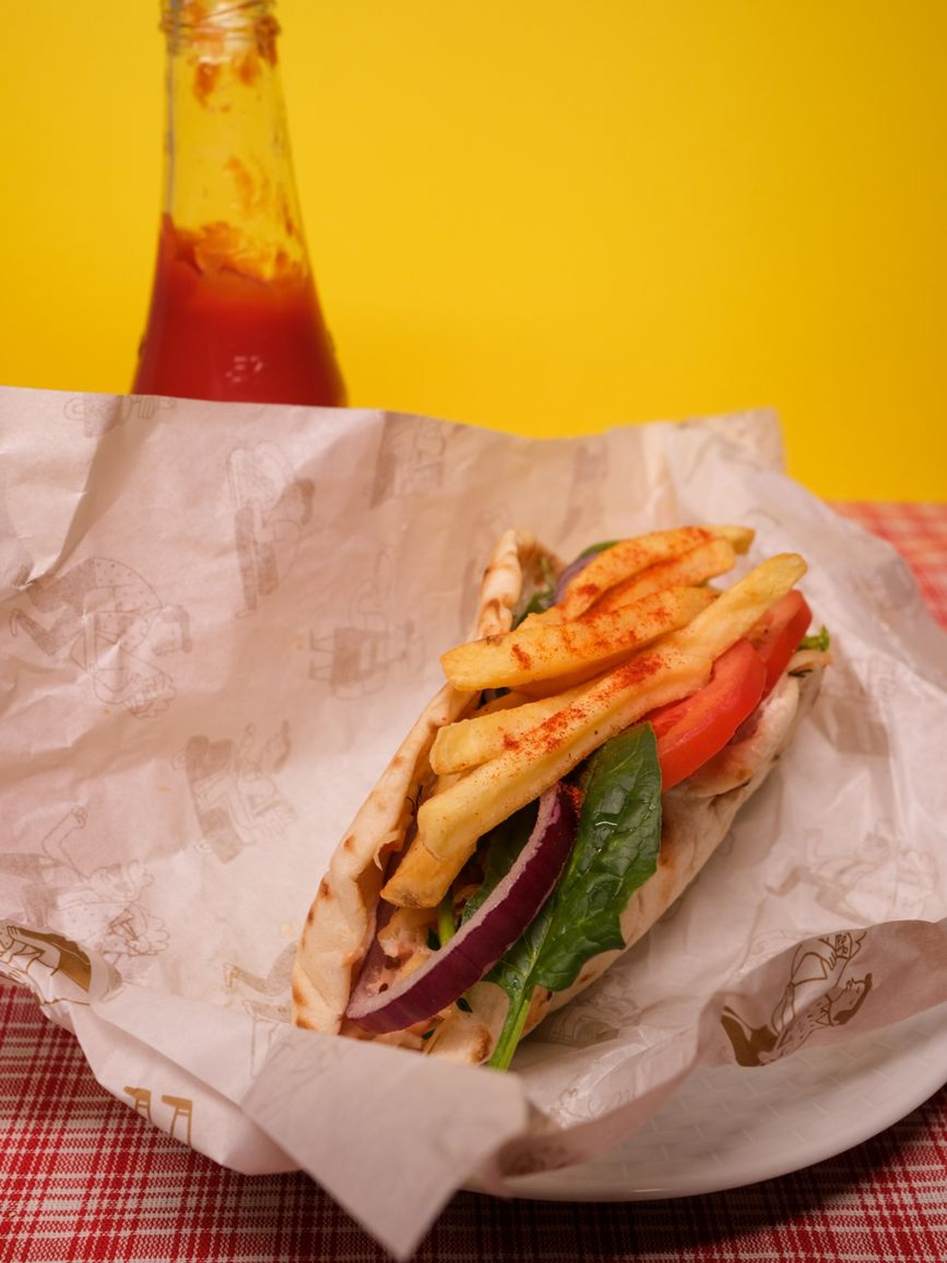 Felülnézet egy asztalról, rajta gyros tálak, friss saláta, köretek és üdítők.